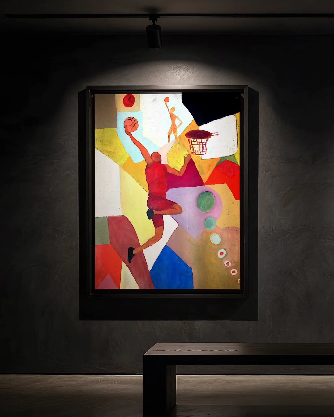 A painting in a thin black frame on a dark plaster wall under a warm spotlight: a basketball player in a red kit leaping to dunk toward a hoop, among flat, angular blocks of colour. A small second figure reaches up near the top; a red disc and a row of small circles sit at the edges.